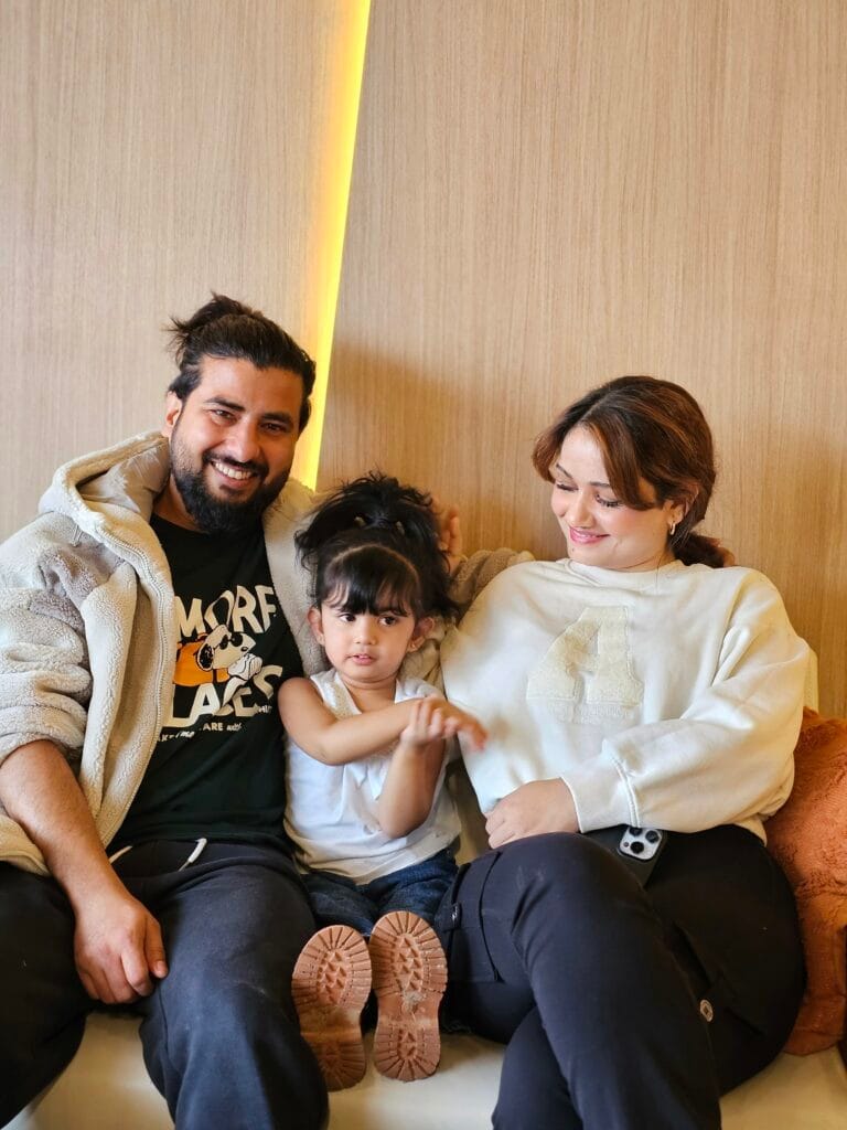 HomeDaddy's founder, his wife, and their young daughter sitting close together on a bench at home, all smiling.